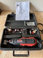 Rotary tool kit open showing tool, accessories, manual