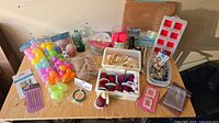 Overview of entire lot on table including eggs, wood pieces, twine, green bottles, pink pom-poms, organizer box, trays with fabric items, silicone molds, comb tool and pouch