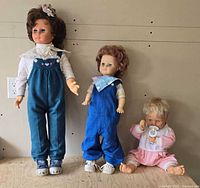 All three vinyl dolls standing/sitting together showing relative sizes and outfits