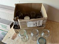 Box containing multiple clear Mason jars viewed from side