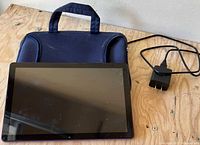 Front view of tablet on wood surface with charger and sleeve