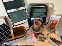 Group shot of all items on table including chairs, tools, pot, trug, seed tray, glass items, cover
