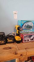 Wide view of drill, chargers, boxed items on workbench