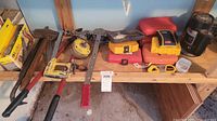 Shelf view showing multiple tools including pull jack, trimmer, bit cases, crowbar and tape measure