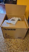 Outer cardboard box labeled nuwave containing cooker components
