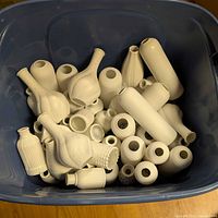 Blue tote filled with numerous small white bud vases