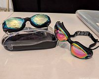Two mirrored swim goggles and hard case on table