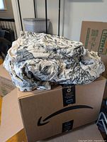 Folded floral cotton duvet cover set on shipping box