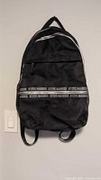 Front view of black Steve Madden backpack hanging on wall