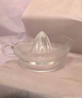 Side view of clear glass citrus reamer showing handle and spout