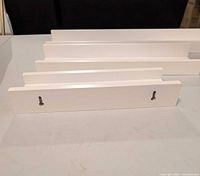 three white floating wall shelves showing back with keyhole slots