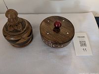 Two lidded containers side by side showing exterior designs and knobs
