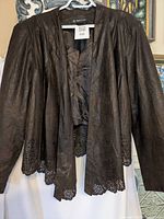 Front view of brown faux suede jacket with laser-cut hem