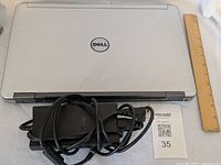 Closed silver Dell Latitude E6540 laptop with Dell AC adapter and power cord