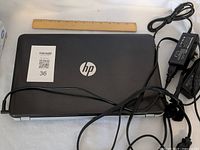 Closed HP Pavilion laptop with HP logo and power cords visible