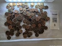 Spread of numerous Canadian pennies on white cloth under light