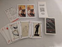 Opened deck spread showing face cards with Toulouse-Lautrec art and jokers, sealed deck alongside