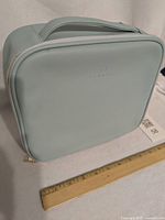 Front view of light aqua Vlando makeup case with carry handle and zipper