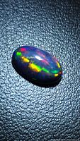 Top view of oval black opal showing multicolour flashes