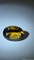 Front view of deep golden oval citrine showing concave faceting