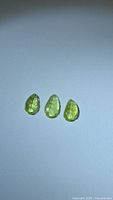 Three chartreuse leaf-carved tourmalines on white background