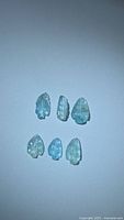 Six leaf-cut Paraiba blue tourmalines arranged in two rows