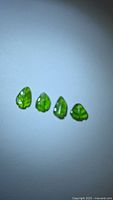 Four green leaf-cut tourmaline stones on white background