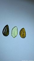 Three leaf-carved tourmaline gemstones in varying colors
