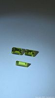 three rectangular vivid green gemstones on background