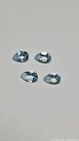 Four pear-shaped blue topaz gemstones on neutral background