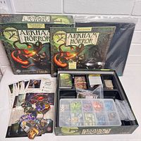 Two Arkham Horror box lids, sealed board, rulebook