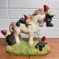 Left side view of unicorn statue with gnomes on grassy base