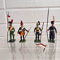 Front view of four painted metal soldiers standing on clear surface