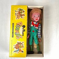Hansel marionette lying in open Pelham Puppets box showing outfit and interior packaging