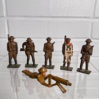 Five standing and one prone metal toy soldiers