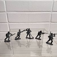Five metal toy soldiers in a row on clear stand