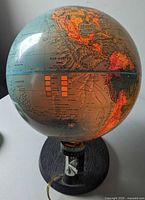 Full view lit globe showing North and South America on wood base