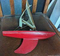 Port side view showing red hull, keel, mast, sail and overall condition