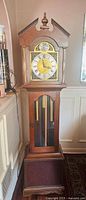 Full view of grandfather clock showing bonnet, dial, weights and base