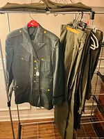 Full view of jacket on hanger and several trousers on rack