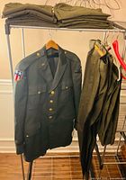 Overall lot view showing dress jacket on hanger and multiple trousers on rack and shelf