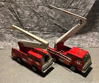 Both Tonka fire trucks side by side showing aerial booms and overall condition