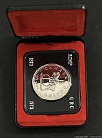Closed clamshell display case opened showing encapsulated coin
