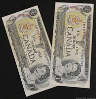 Front view of both 1973 $1 Canadian banknotes showing Queen Elizabeth II and consecutive serial numbers