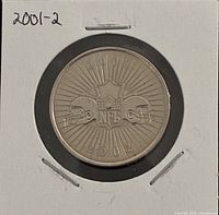 Obverse of coin with NFL shield, helmets, sunburst and 2001 2002 text