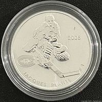 Reverse of encapsulated silver coin featuring Jacques Plante design