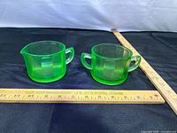 Front view of creamer and sugar bowl with rulers for scale showing neon green uranium glass pieces