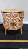 Front view of wicker sewing basket on legs with tag