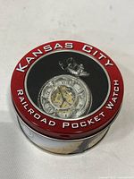 Tin display case showing watch through clear window