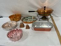 Overall lot layout showing chafing dish, molds, loaf pan, enamel dish and bells